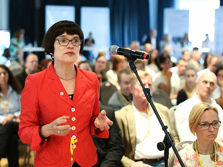 Frau in rotem Blazer am Mikrofon beim SIQ! Forum 2016.