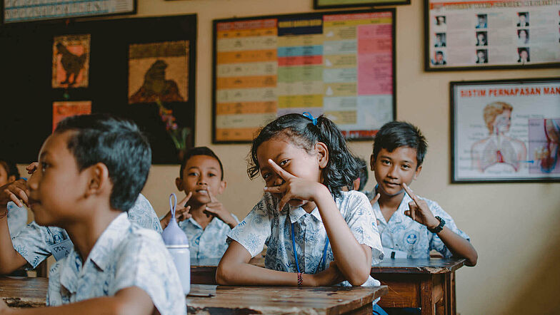 Schulkinder auf Bali im Klassenraum zeigen Peace-Zeichen.