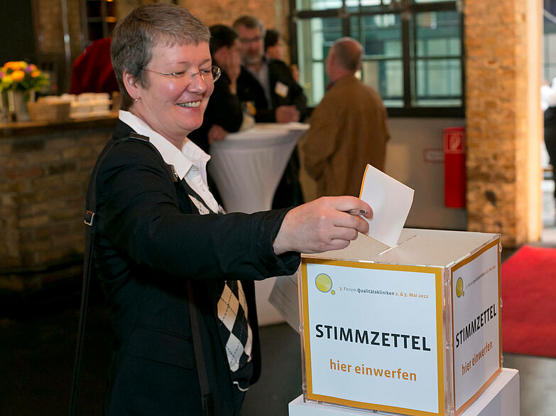Kurzhaarige Frau wirft Stimmzettel in Wahlurne