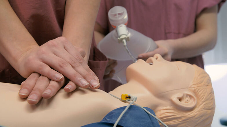 Eine Person trainiert die Herzdruckmassage an einer Puppe.