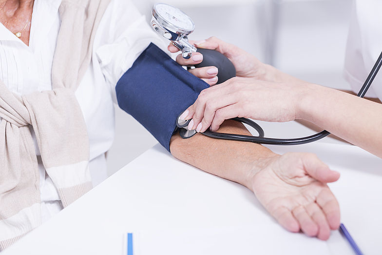 Blutdruckmessen bei einer Person mit Manschette und Stethoskop.