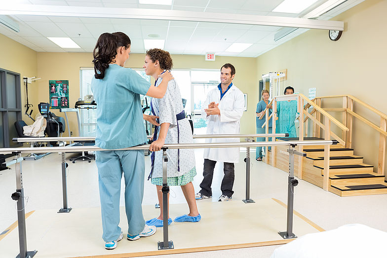 Patientin bei der Physiotherapie um wieder laufen zu lernen.