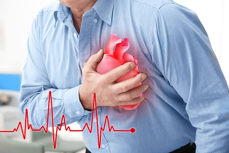 Mann hält sich die Brust auf Höhe des Herzens aufgrund von Schmerzen.