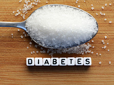 Zucker auf einem Essläufel sowie dem Schriftzug Diabetes